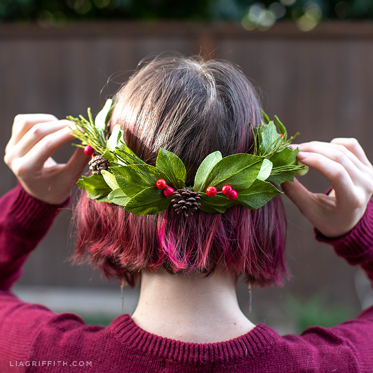 Woman putting crepe paper winter evergreen wreath on her head