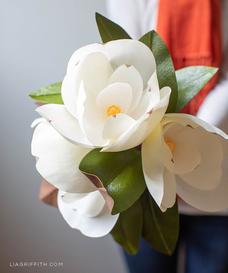 person holding crepe paper magnolias