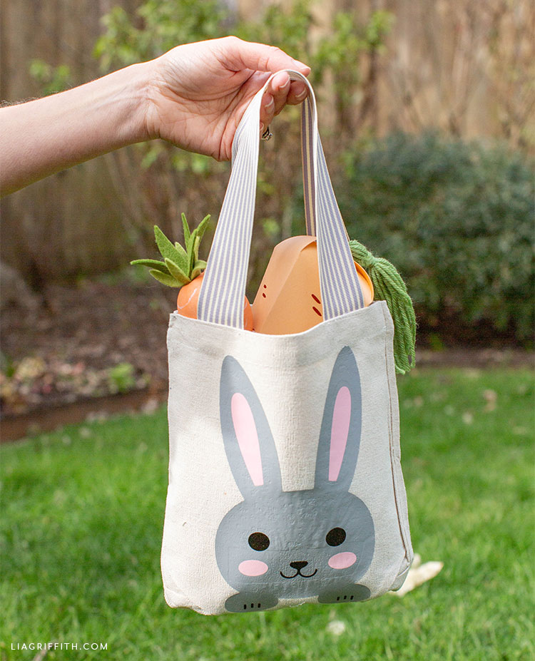 Person holding Easter tote bag with paper and felt carrots in backyard