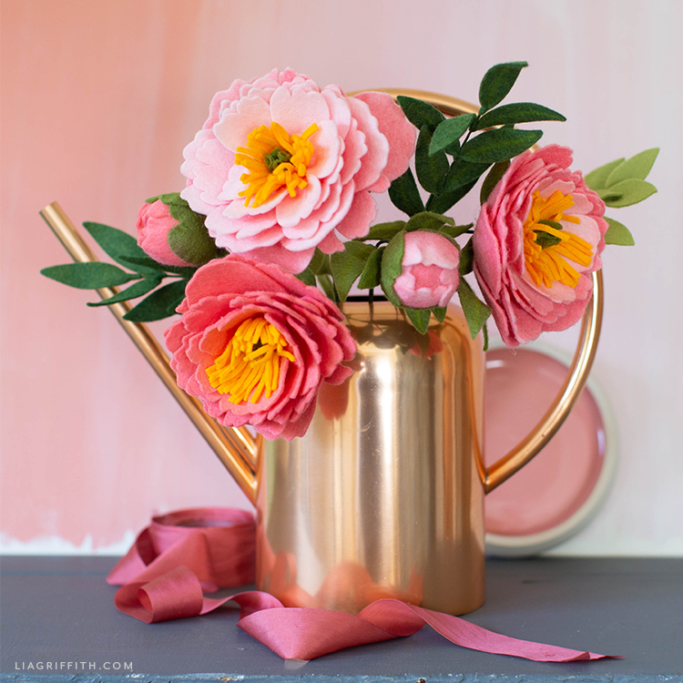 felt coral charm peony flowers and buds in gold vase with pink ribbon on ground