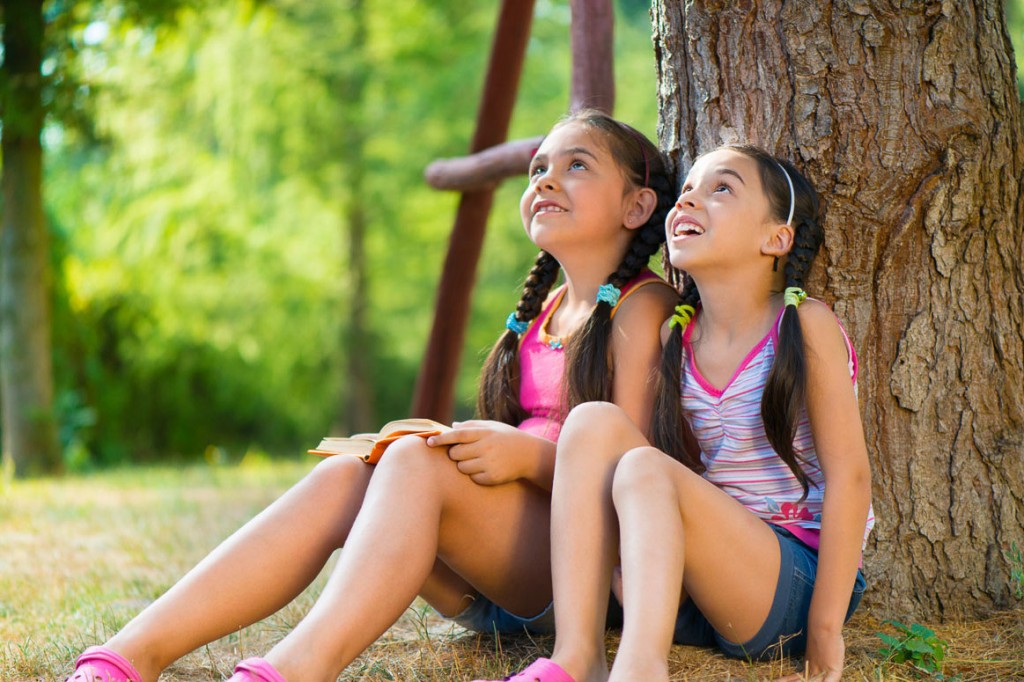 Hispanic sisters sitting under the tree and talking