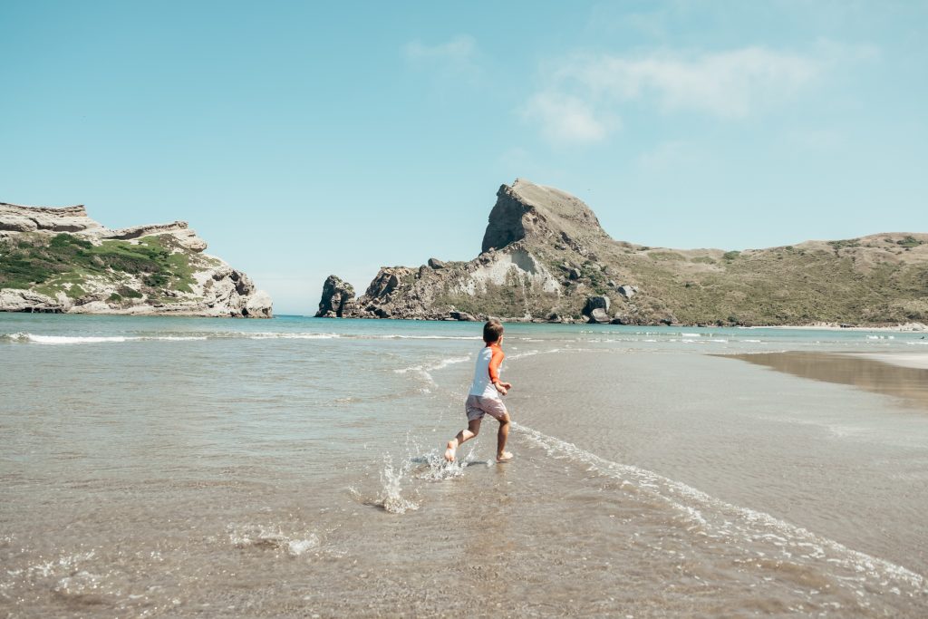 Boy running on Castlepoint Beach in New Zealand