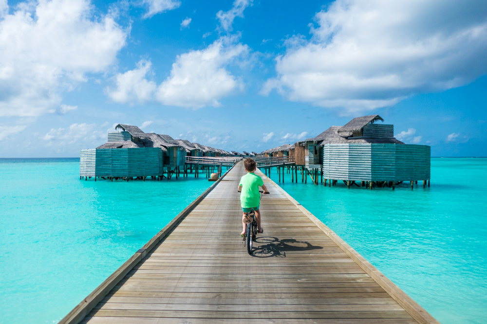 Boy rides bike on beach boardwalk