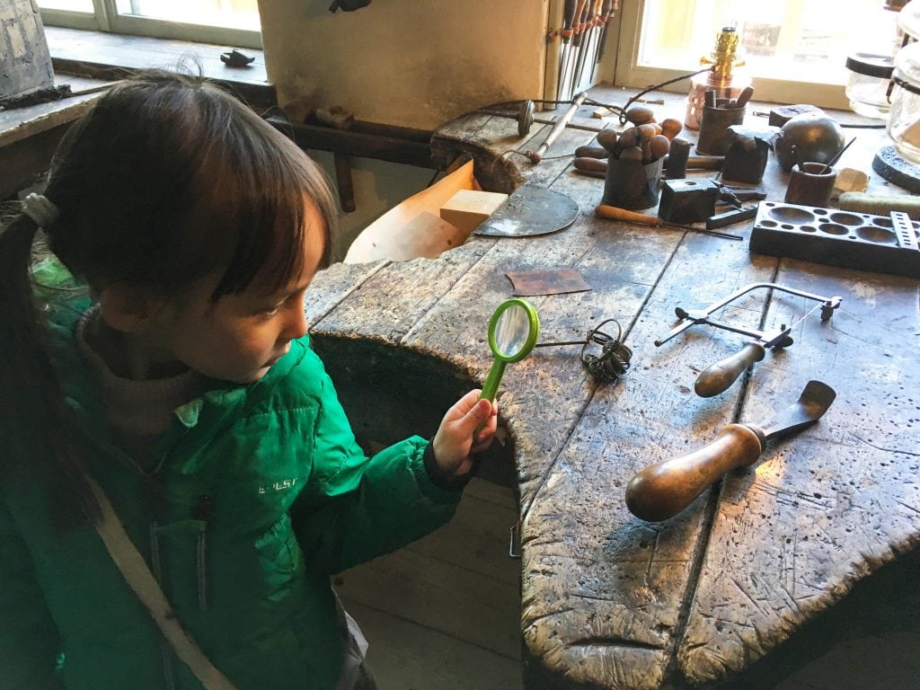 Things to do in Stockholm with kids_Girl in Skansen looking at blacksmith tools