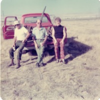 Harry Anderson, another man, and woman seated on tailgate of truck<br />
