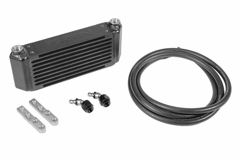 A black PERRIN Transmission Oil Cooler displayed with mounting brackets, fittings, and hose for installation.