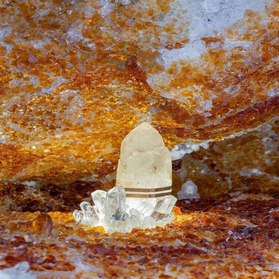 Translucent crystal surrounded by orange and white crystalline structures.