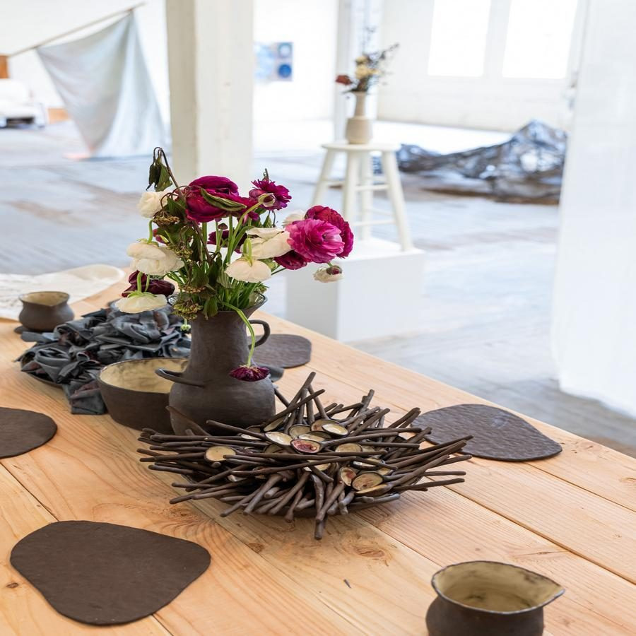 Table with art objects and a floral arrangement in a bright exhibition space.