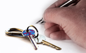 Keys next to hand holding pen.