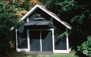 Gray storage shed surrounded by trees