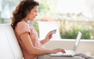 Woman with laptop and computer working on improving her credit score.