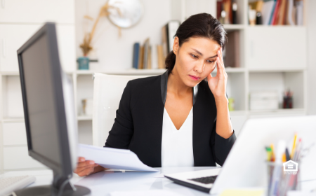 Woman looking at computer worried about tenant fraud.