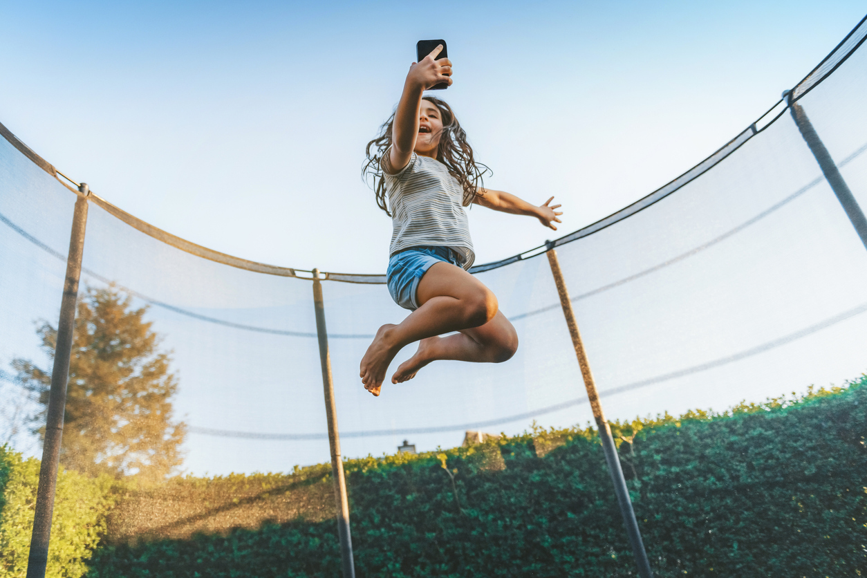 Little Girl Jumping on Trampoline in Backyard Real Property