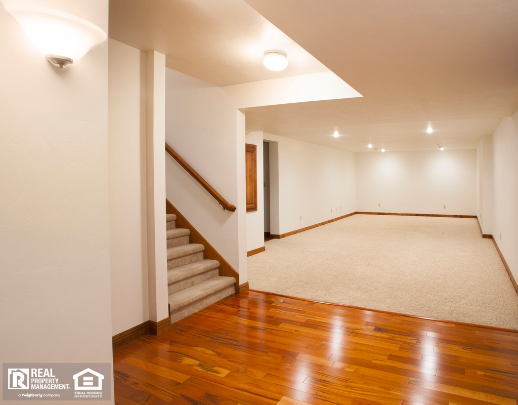 View of the Newly Finished and Unfurnished Basement with Hardwood Flooring