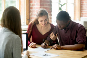 couple signing lease agreement in front of leasing agent