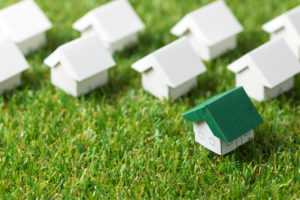 House with green roof among the white on the grass, for real estate property or eco friendly house concept