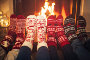 four friends wearing colourful wool socks warming their feet by the fireplace