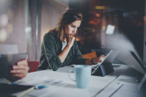 woman working on a tablet next to colleague late at night in a modern office loft