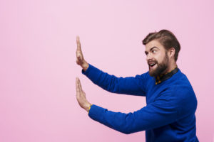 man putting hands up to distance from someone or something not shown