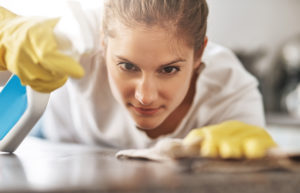image of woman spot cleaning a table wearing gloves looking very determined to the detail of what she's doing