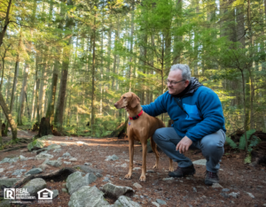 Mature Hiking Man Holding Vizsla Dog in Sunlit Forest