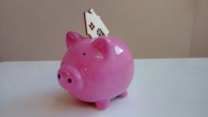 House cutout in piggy bank on white desk