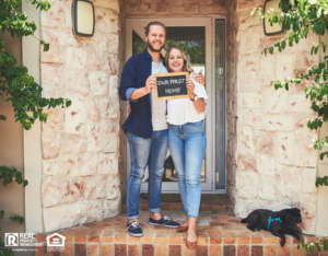 Portrait of a young couple holding a chalkboard with "our first home" written on it