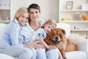 Happy Family Posing on a White Couch with their Dog
