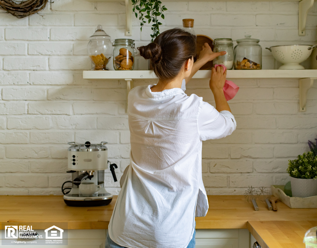 Woman Dusting Kitchen Shelves with a Microfiber Duster