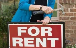 Property Owners Placing a For Rent Sign on a Rental Property