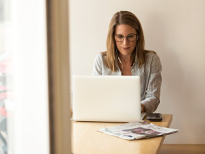 A Woman Typing on Her Laptop at the Kitchen Table