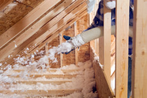 Spraying Blow-In Fiberglass Insulation Between the Attic Trusses of Your California Rental Home