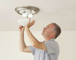 Lexington Park Property Manager Placing Energy Efficient Lightbulbs in a Fixture