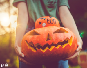 Charles County Resident Holding a Stack of a Decorated Pumpkin and a Jack-o-Lantern