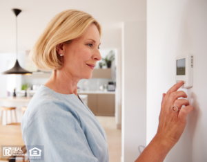 Older Woman Adjusting the Thermostat in Her Home