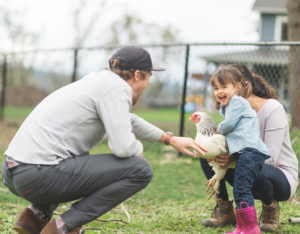 Happy Family Playing with a Chicken in the Yard of their Chesterfield County Rental Home