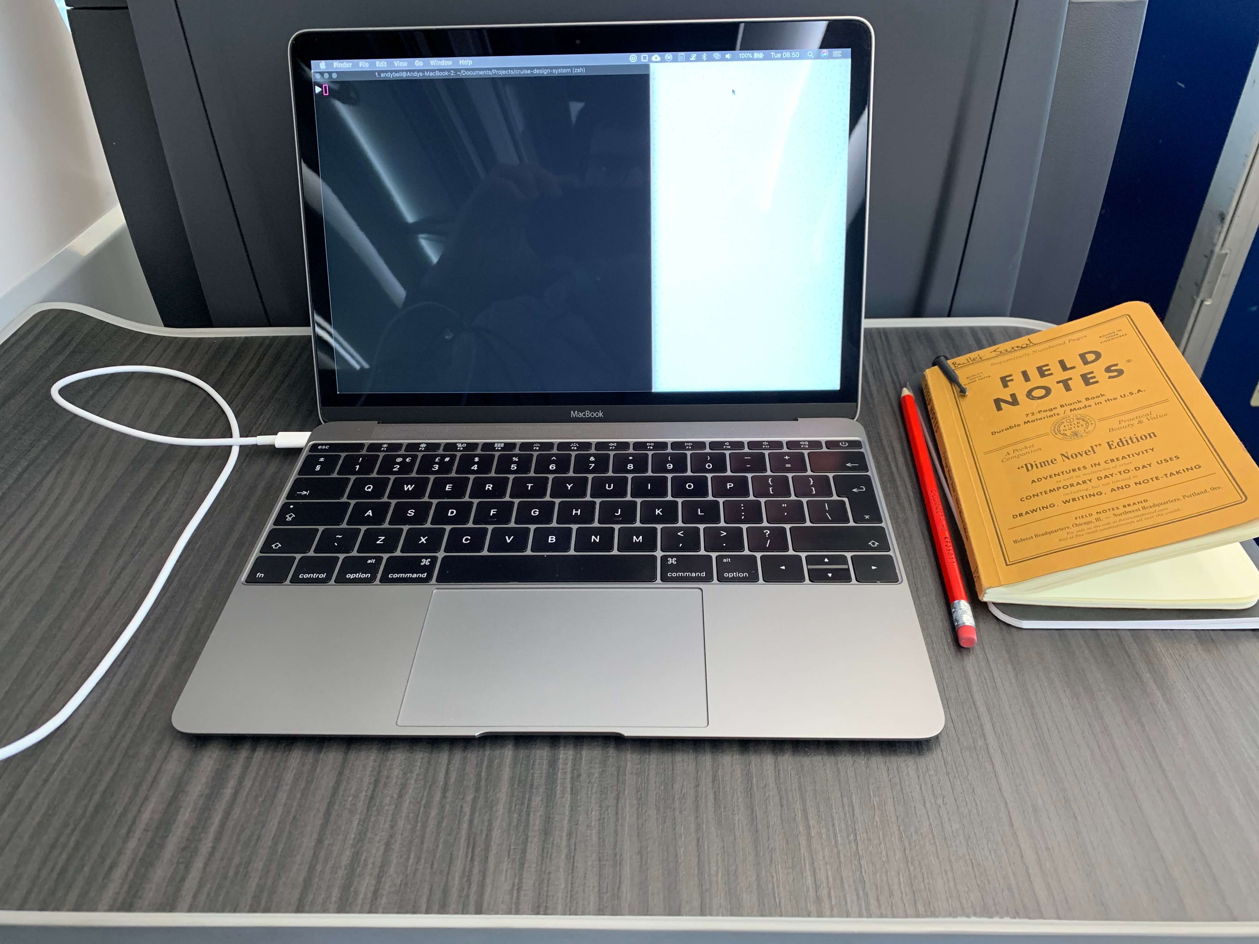 A laptop on a train table with a notebook and pencil