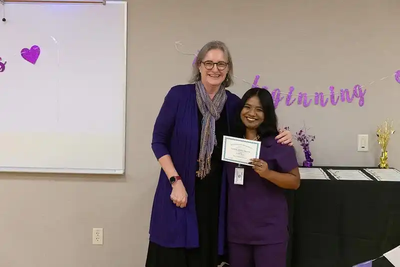 two women posing with a certificate