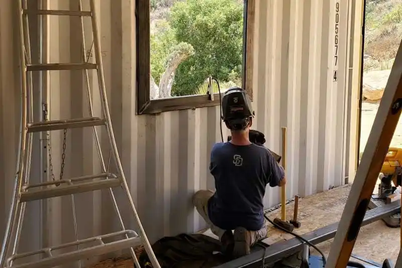 a person working on a house made from a cargo container