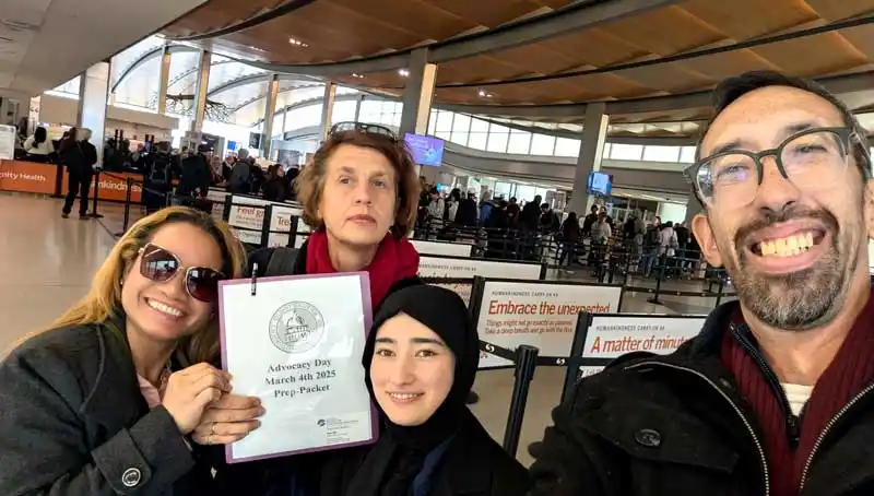 Four people taking selfie, one holding document labeled Advocacy Day.