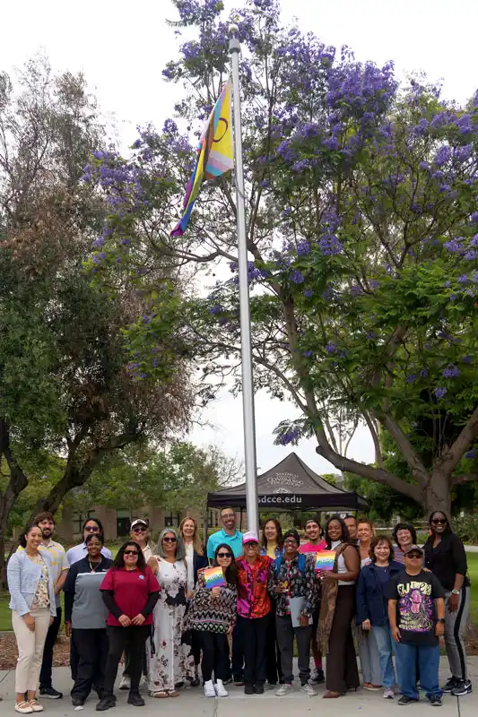 a group of people in front of a flag pole and pride flag