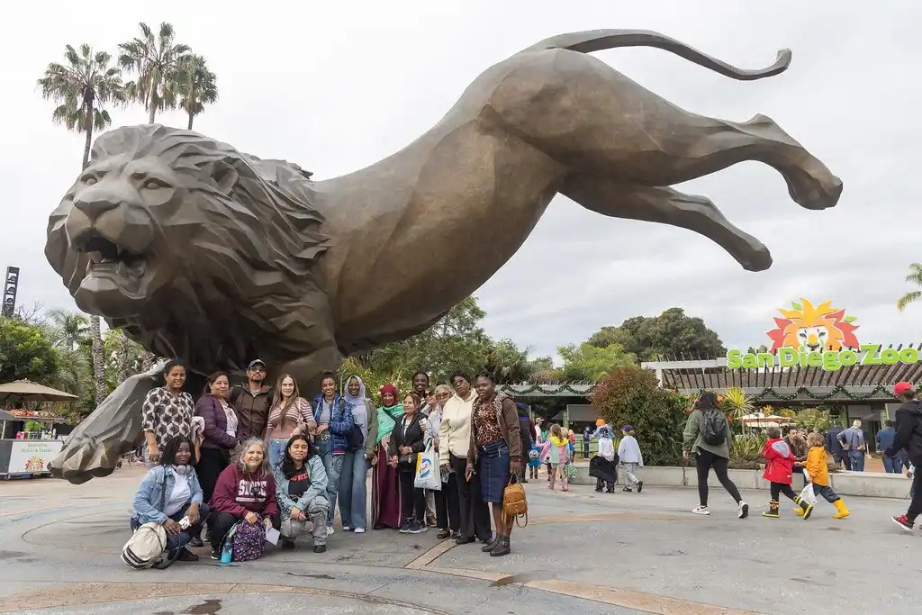 group of people below a giant lion statue