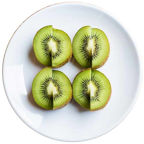 A photograph of sliced kiwifruit on a while plate