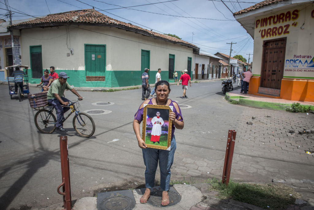 Doña Ivania Dolmus sostiene el cuadro de su hijo Sandor en el punto exacto donde lo asesinó una bala de francotirador el pasado 14 de junio. LA PRENSA / Óscar Navarrete