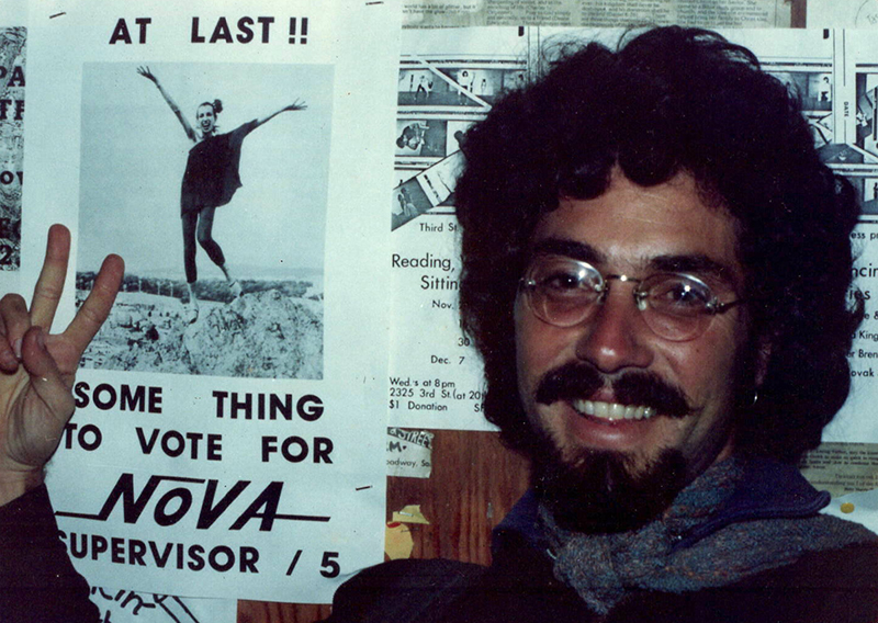 Aaron Shurin on Castro Street, in front of a poster of Silvana Nova which he helped create, ca. 1977.