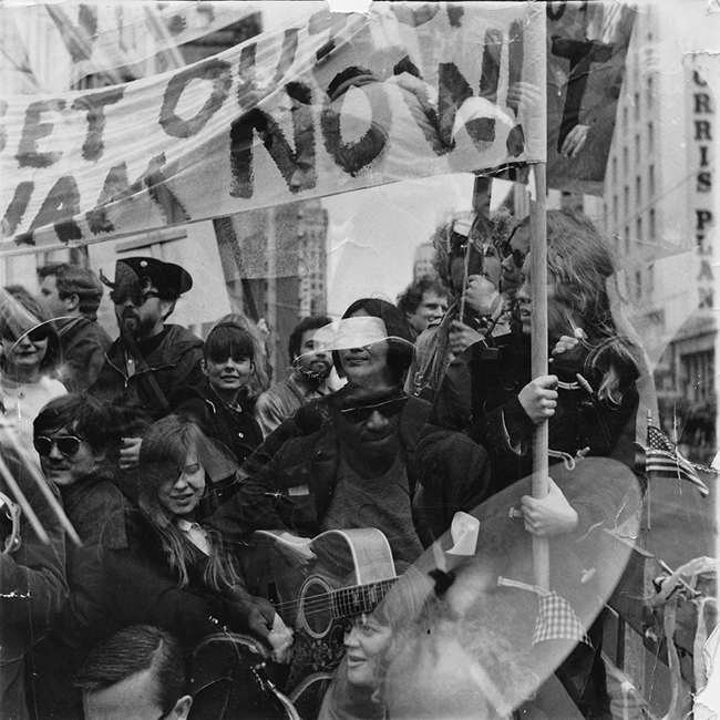 Mike Henderson playing guitar during a Vietnam War demonstration, date and photographer unknown.
