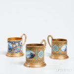 Three Russian Enameled Brass Cups with Scenic Medallions, 20th century (Estimate: $300-500)