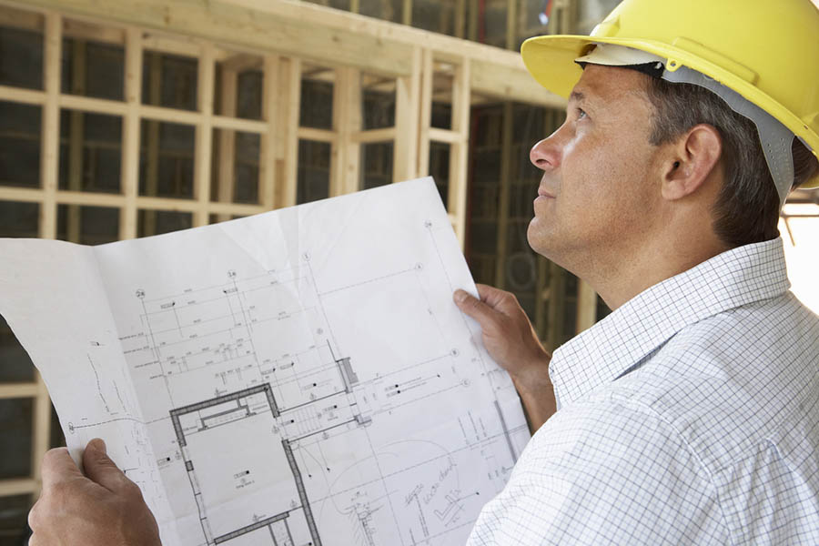 Male contractor reviewing plans and newly built house