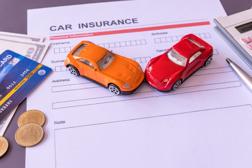 Two toy cars placed on a car insurance application form, symbolizing auto insurance coverage and accident protection.