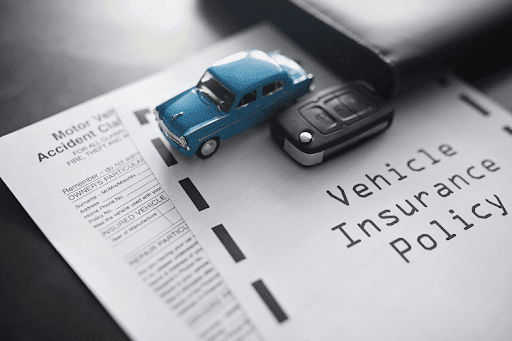 Miniature car resting on top of an auto insurance policy form.